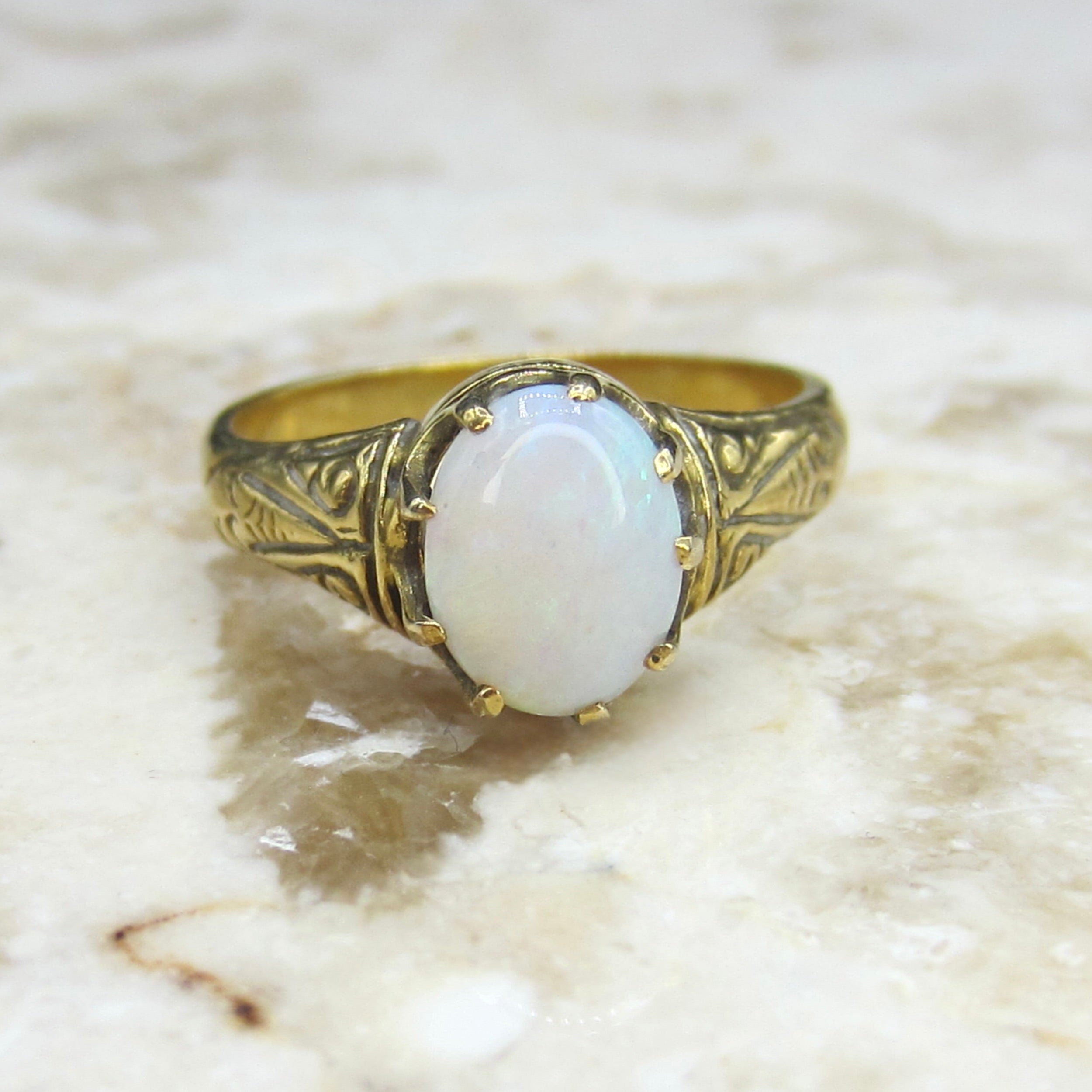 Gold ring with a white stone on a marble surface