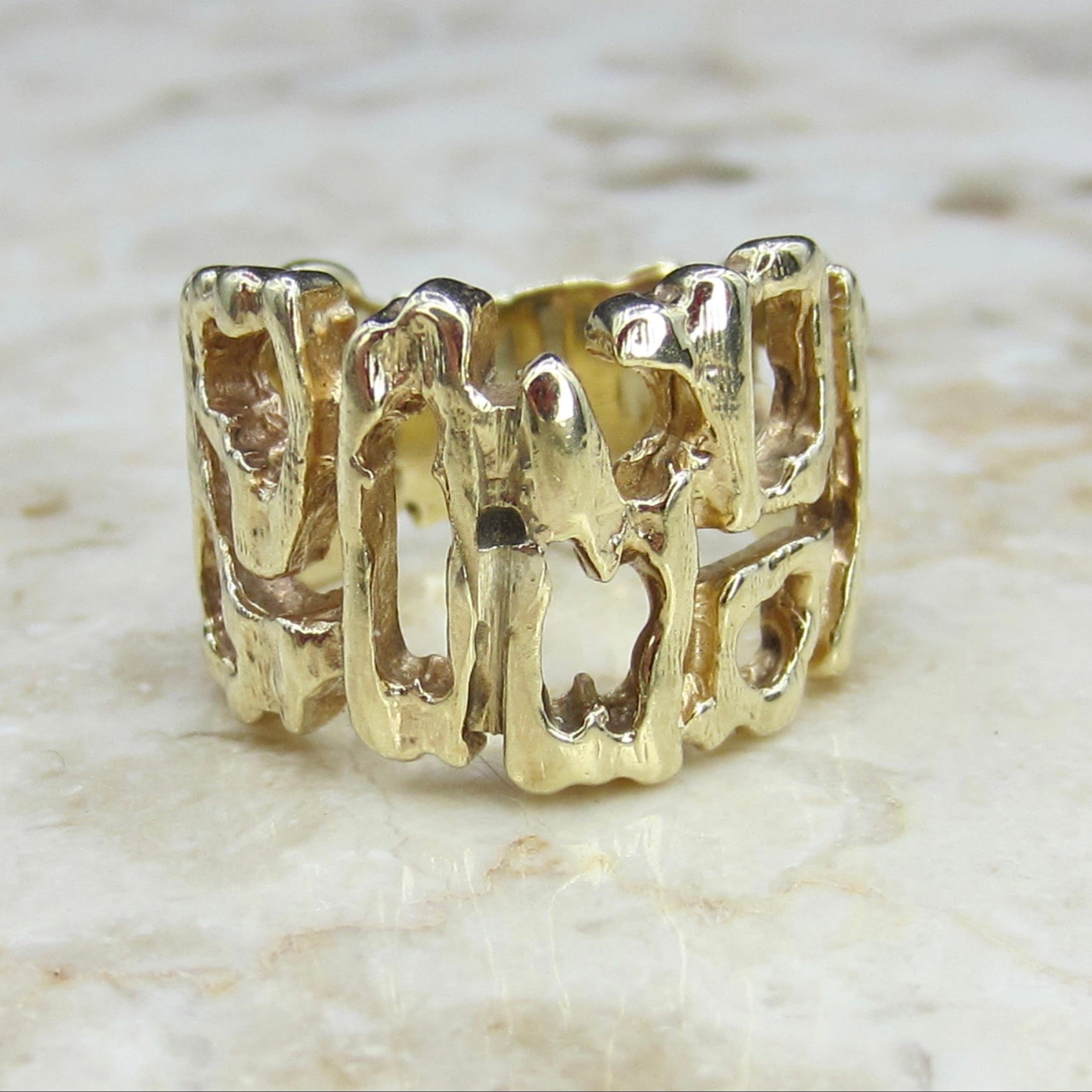 Gold ring with a textured design on a light marble background