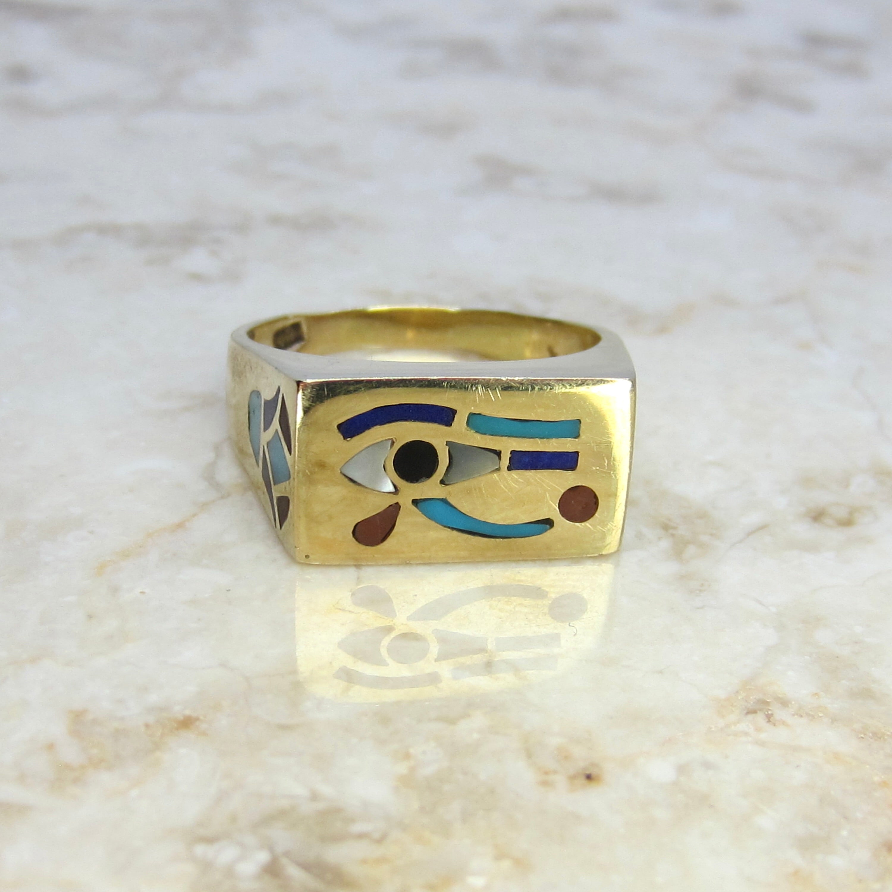 Gold ring with eye design on a marble surface