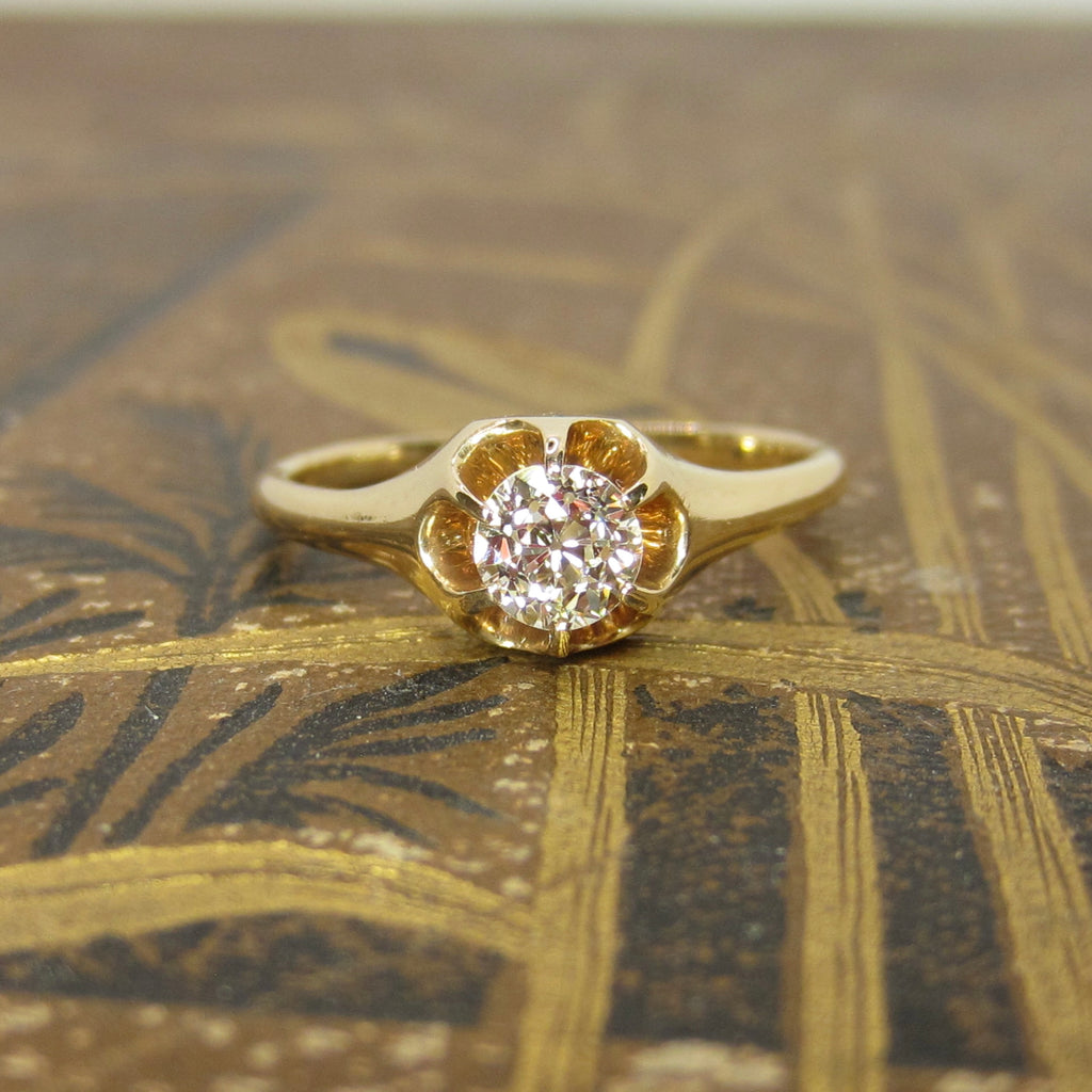Gold ring with a diamond on a textured gold surface