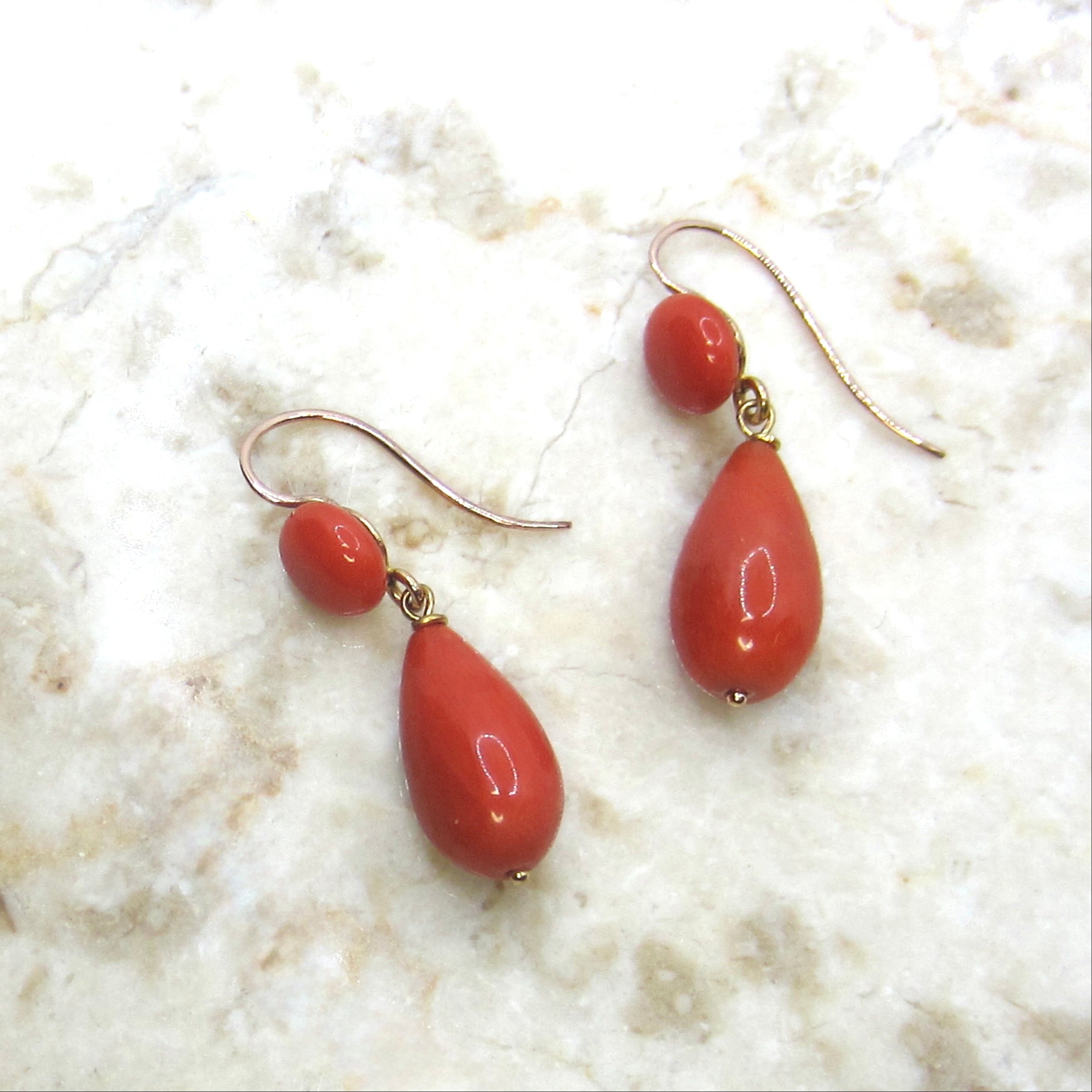 Pair of red teardrop earrings on a light marble background