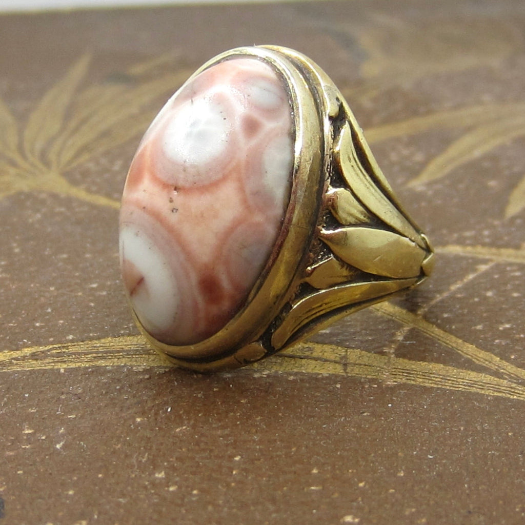 Gold ring with a pink stone on a textured surface