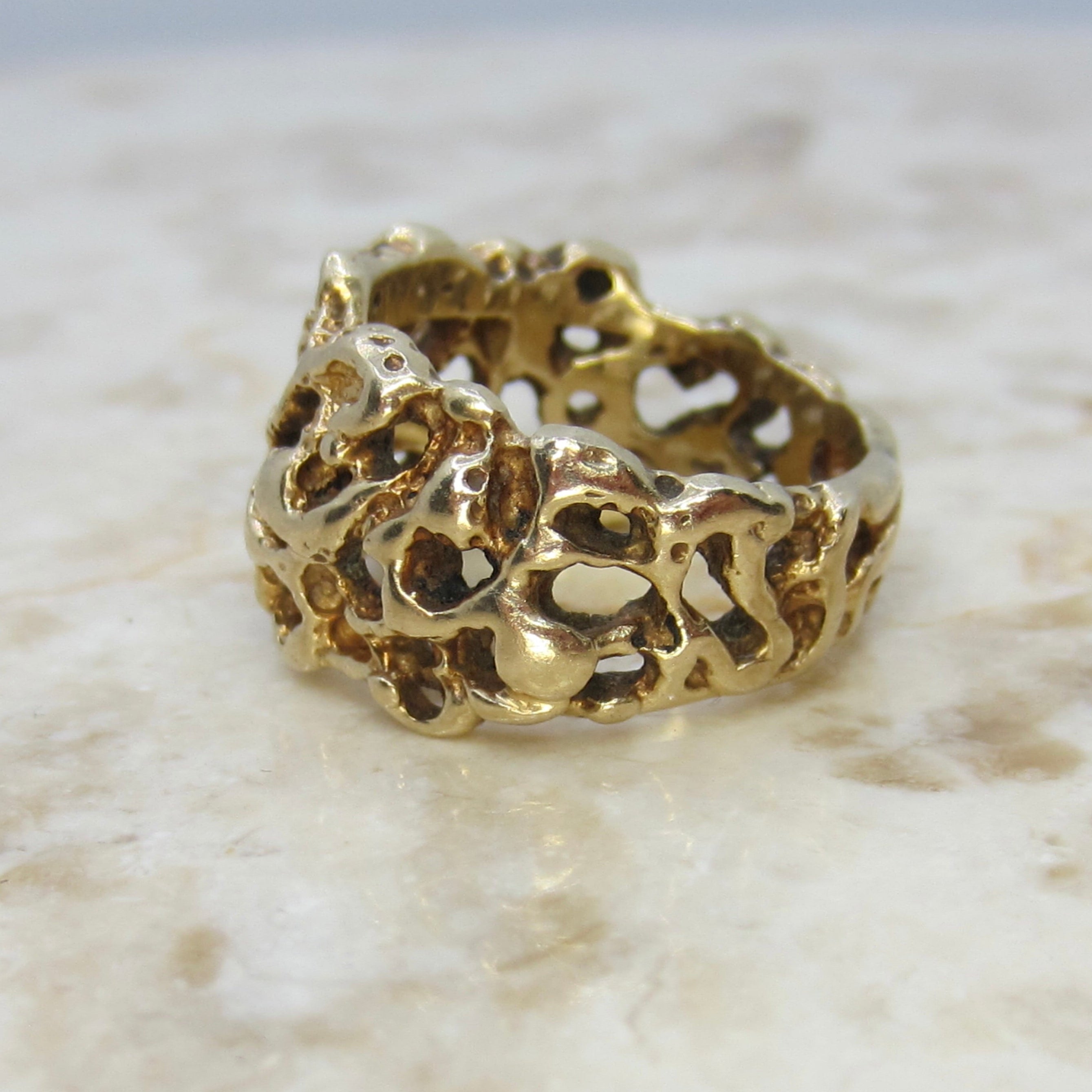 Gold ring with intricate design on a marble surface