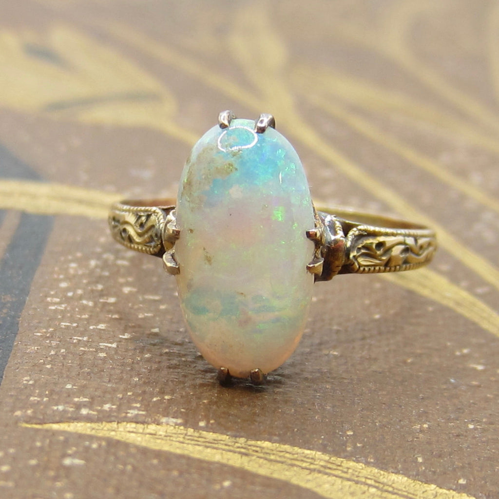Opal ring with gold setting on a textured surface