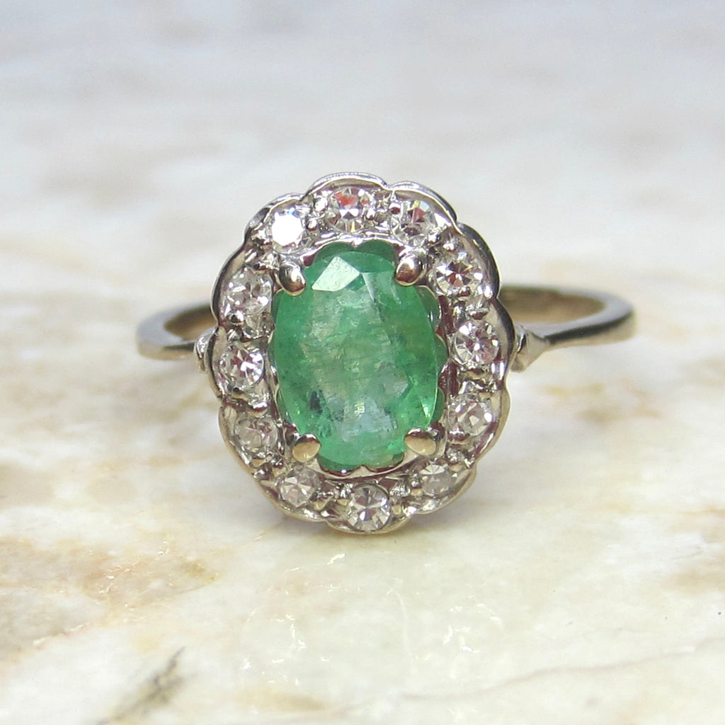 Ring with a green gemstone and diamond accents on a marble surface