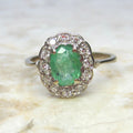 Ring with a green gemstone and diamond accents on a marble surface