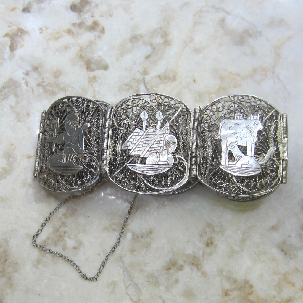 Decorative silver belt buckle with intricate designs on a marble surface