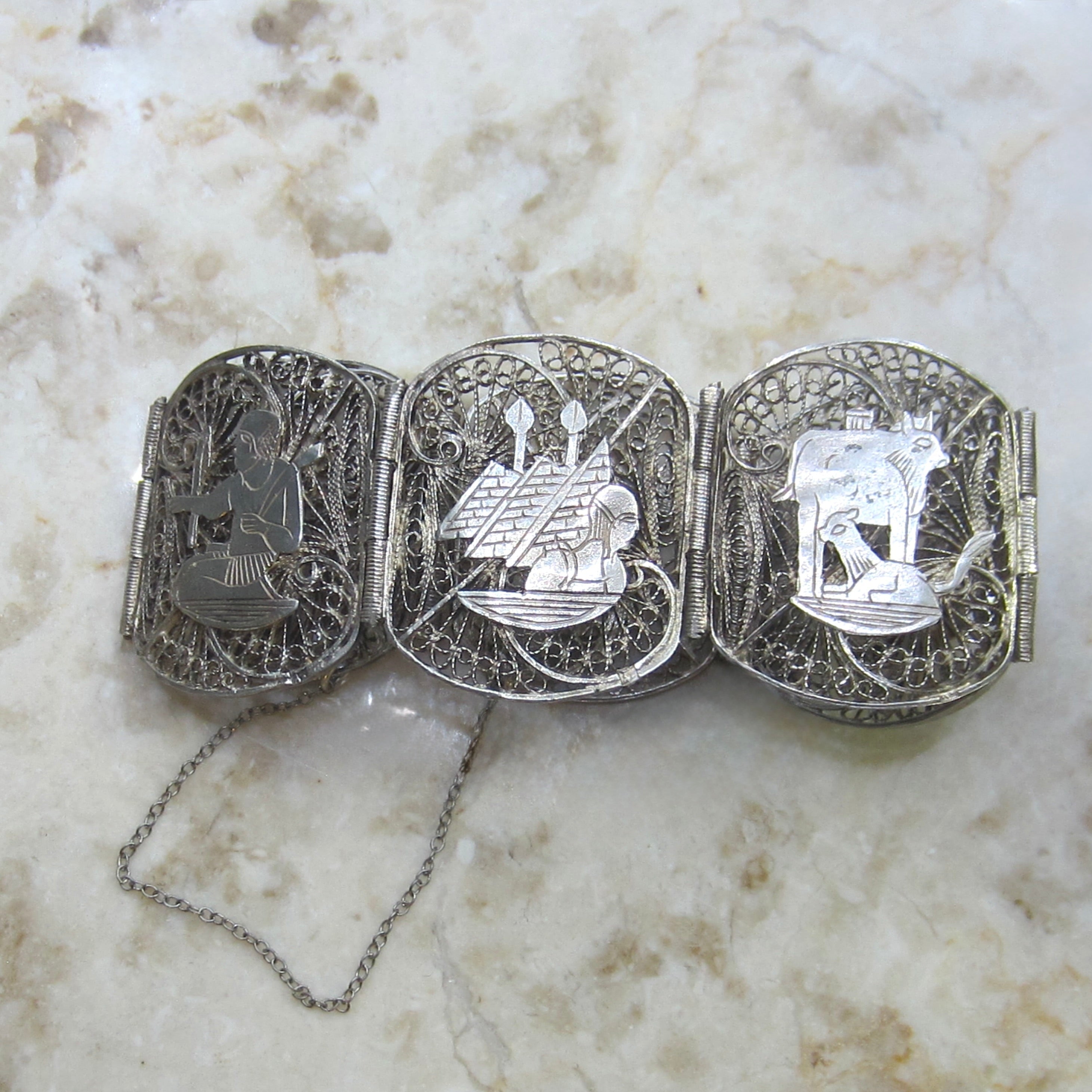 Decorative silver belt buckle with intricate designs on a marble surface