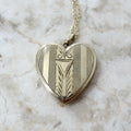 Heart-shaped silver locket with intricate designs on a marble surface