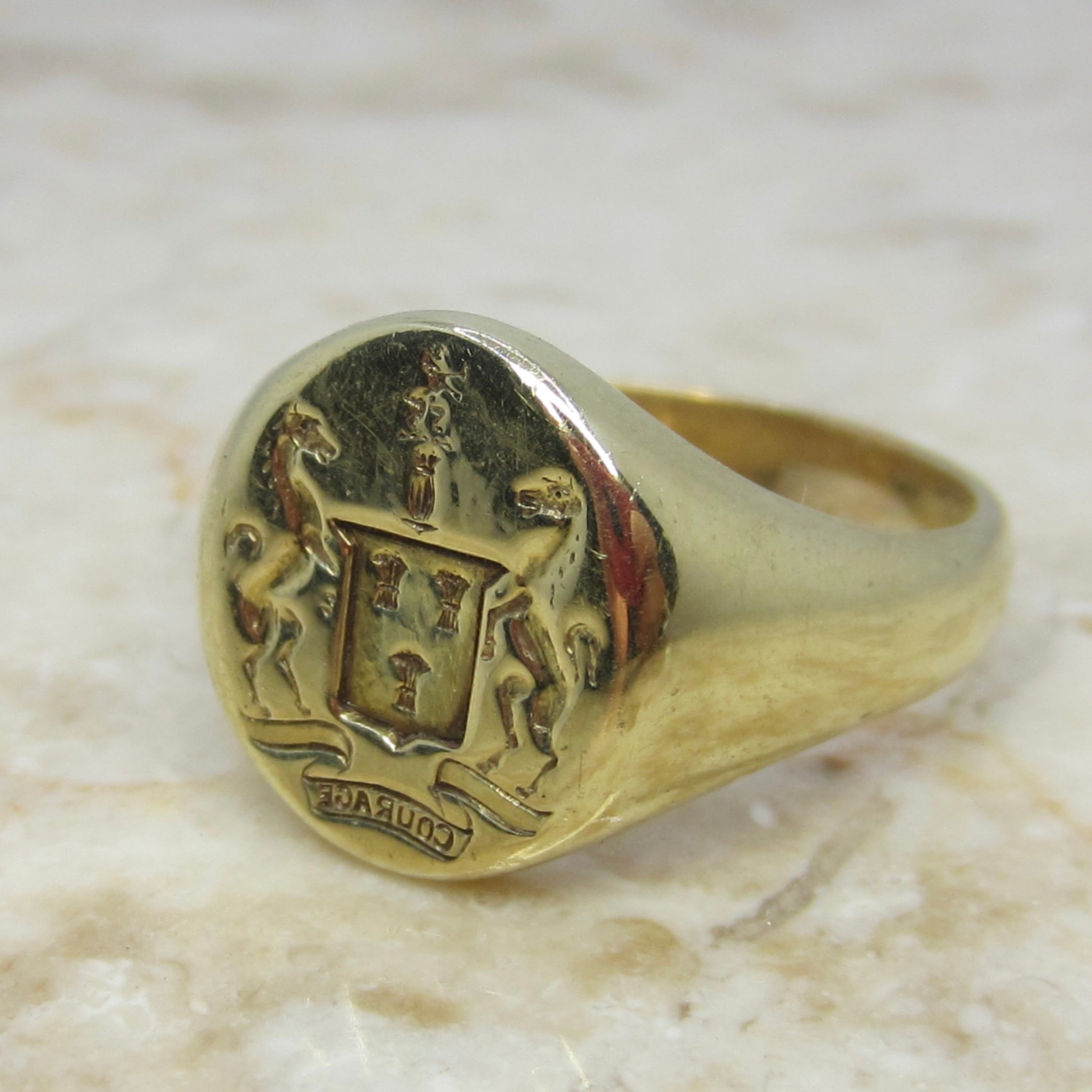 Gold ring with a detailed emblem on a marble surface