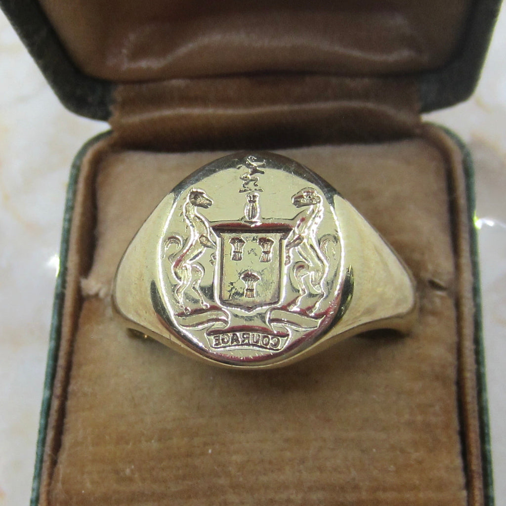 Silver ring with emblem in a brown jewelry box on a marble surface