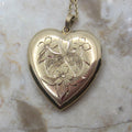 Heart-shaped gold locket with floral designs on a marble surface
