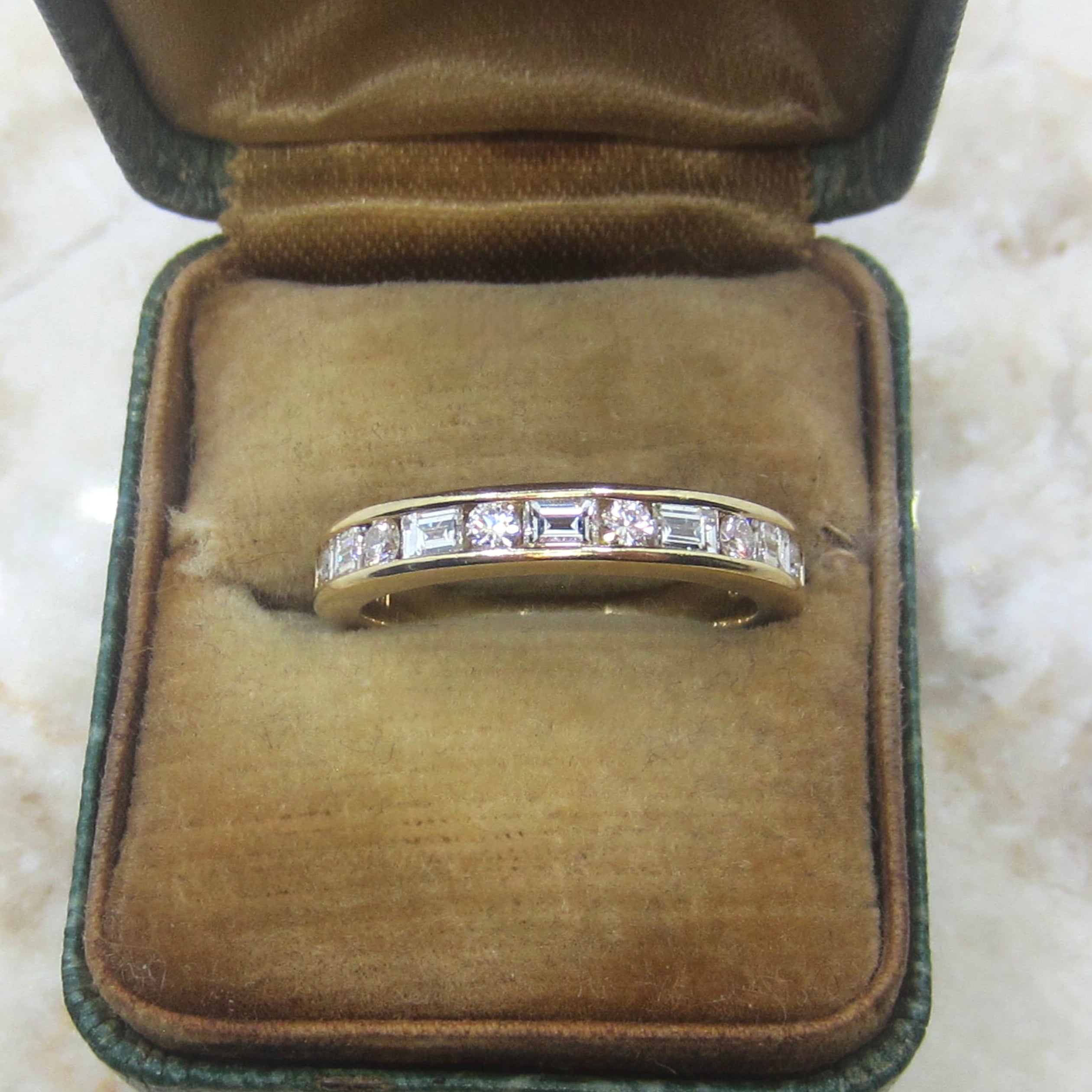 Gold ring with diamonds in a brown velvet box on a marble surface