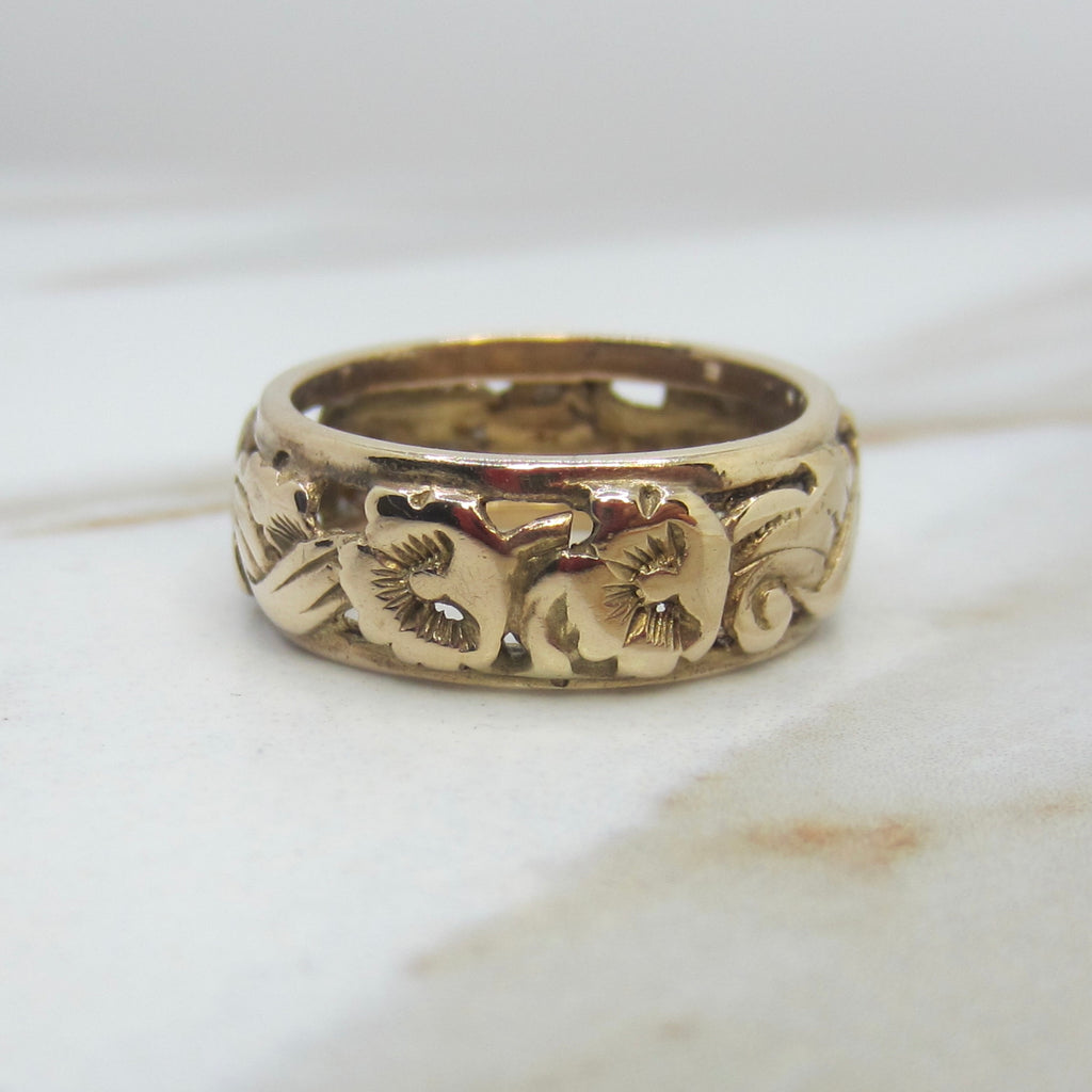 Gold ring with floral engraving on a marble surface