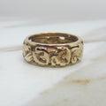 Gold ring with floral engraving on a marble surface