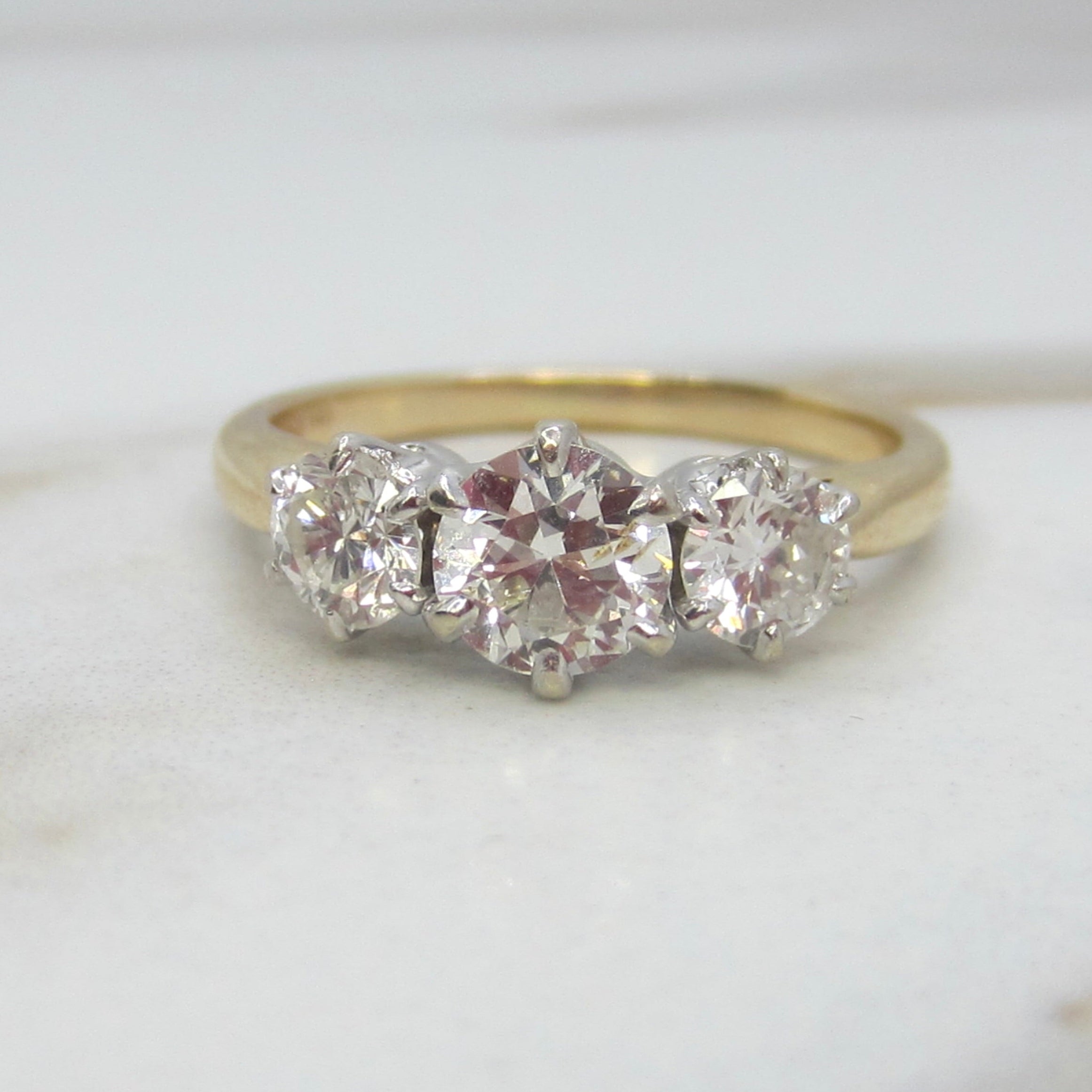 Gold ring with three diamonds on a light background