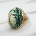Decorative ring with green stone and gold band on a white background
