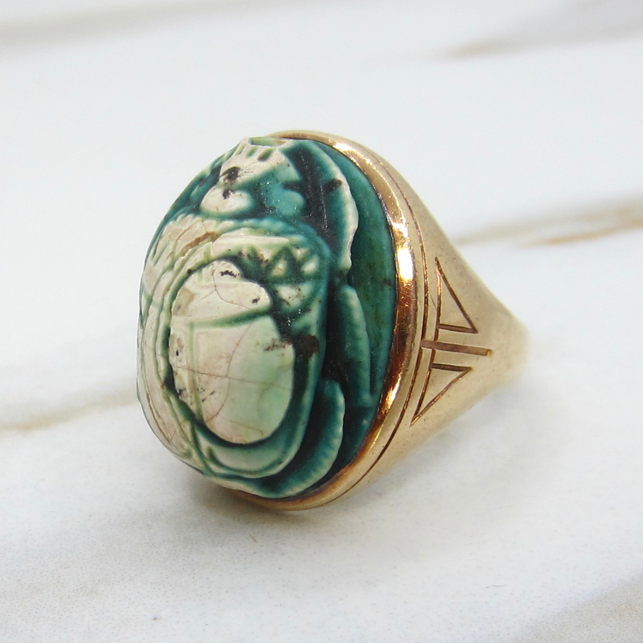 Decorative ring with green stone and gold band on a white background