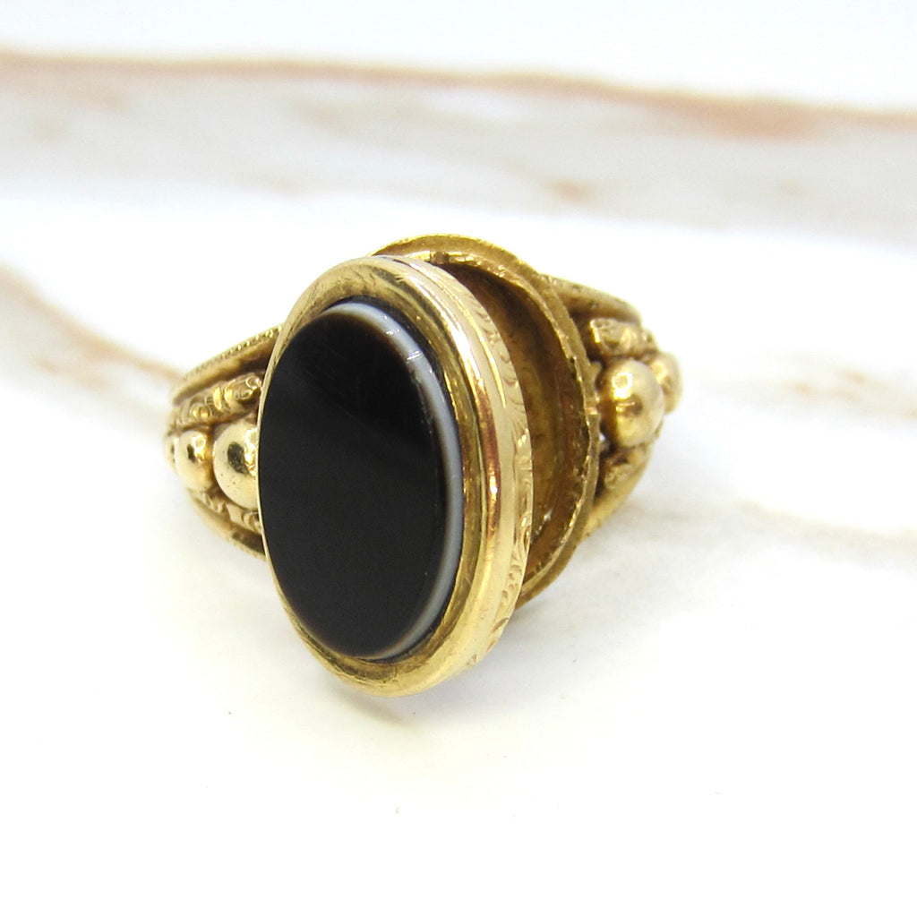 Decorative ring with black stone and gold band on a white background