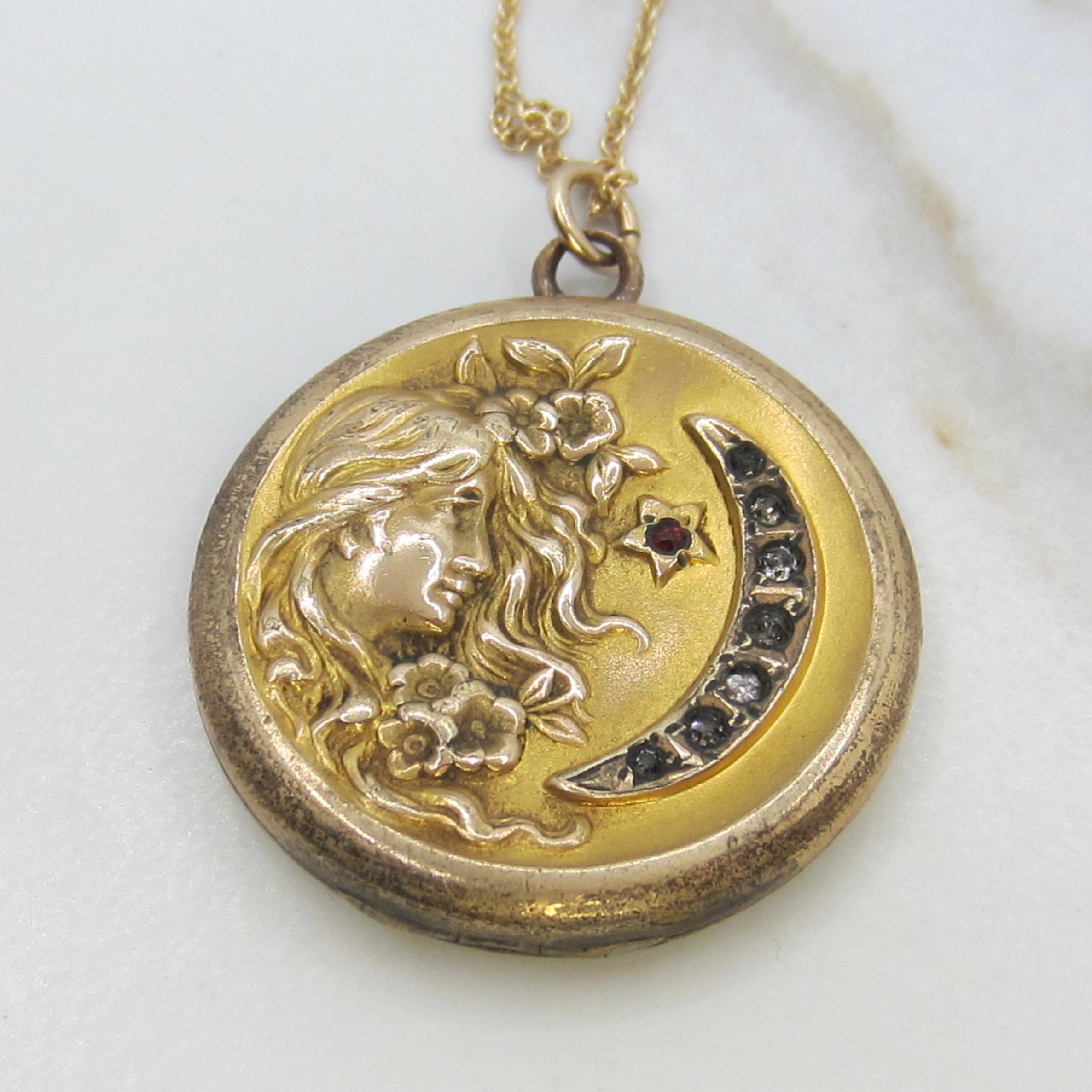Gold necklace with a round pendant featuring a unicorn design on a white background