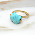 Gold ring with a turquoise stone on a marble surface