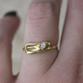 An antique 18k gold snake ring with a rose cut diamond in the center, on a human hand.