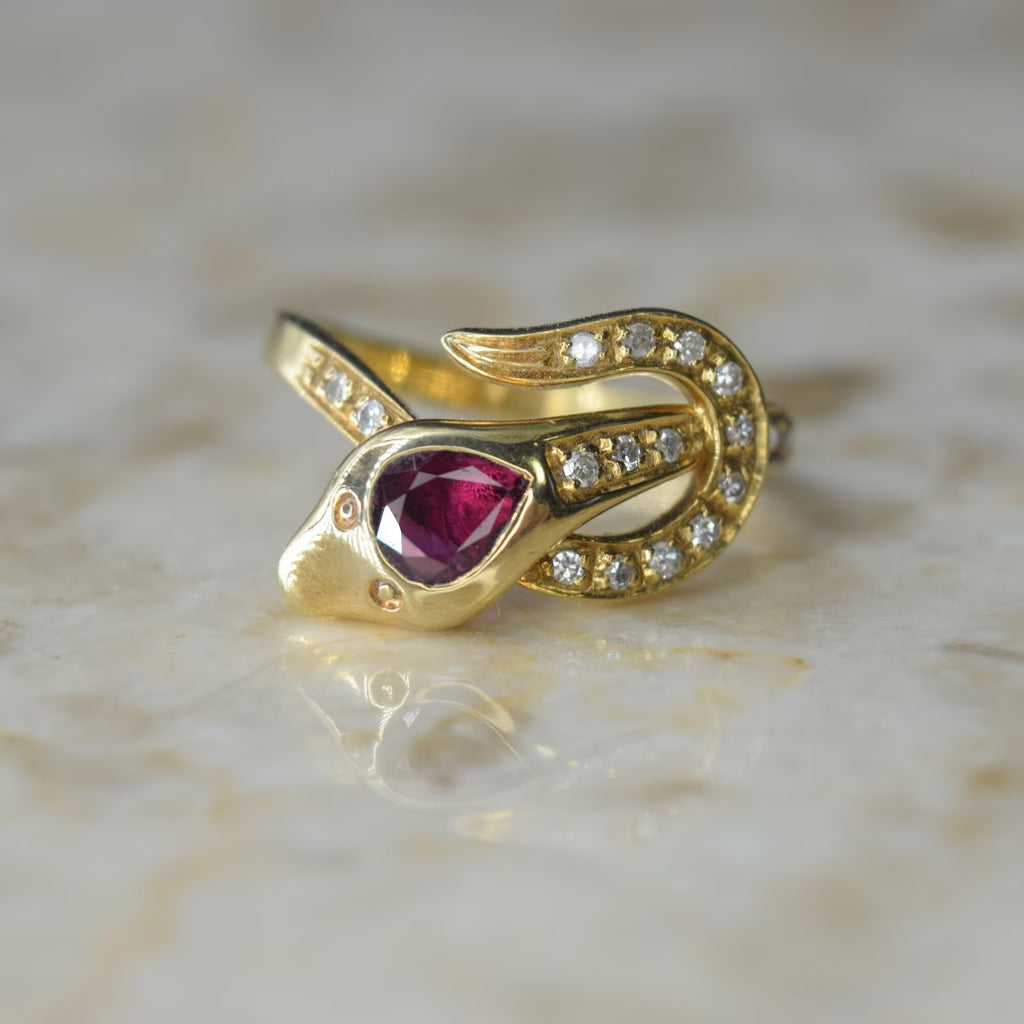 A vintage 18k gold ruby and diamond snake ring with a face design, set with diamonds on the shoulders.